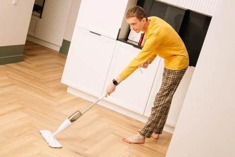 Hard-working middle aged man barefoot cleaning in living room and washing flo Foto stock
