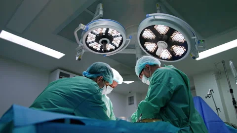 Hard-working surgeons bent over the operational table.  Stock Footage 252641624