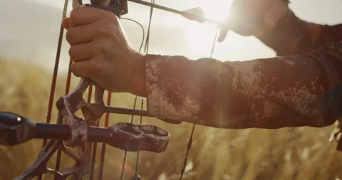 Hardened bowhunter draws back arrow bathed in light Stock Footage 101126540