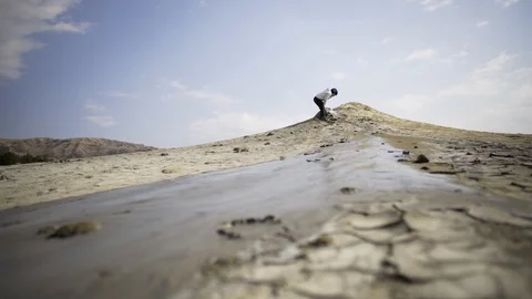 Hardened stream of volcano mud in a lunar landscape. Children play near crater. Stock Footage 105176072