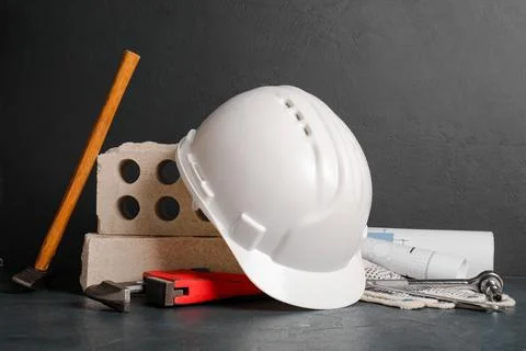 Hardhat with bricks and set of construction tools on black grunge background Stock Photos
