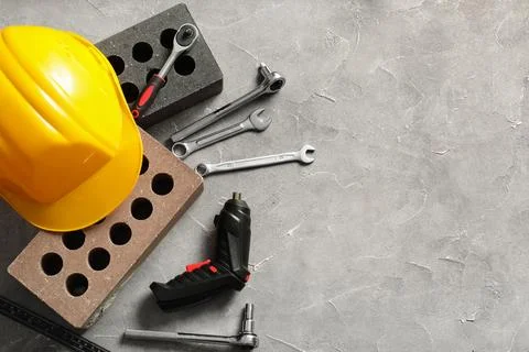 Hardhat with bricks and set of construction tools on grey grunge background Stock Photos