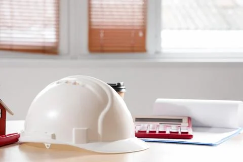 Hardhat with calculator on table in office, closeup Stock Photos