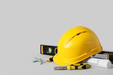 Hardhat with construction tools and house plan on grey background Stock Photos