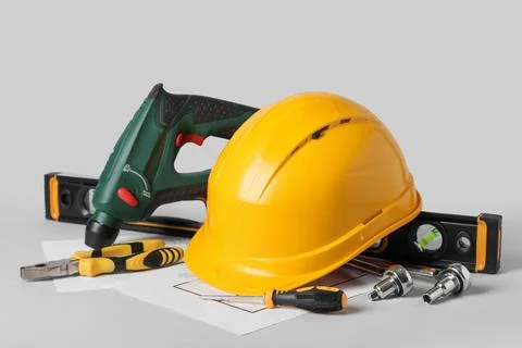 Hardhat with construction tools and house plan on grey background Stock Photos