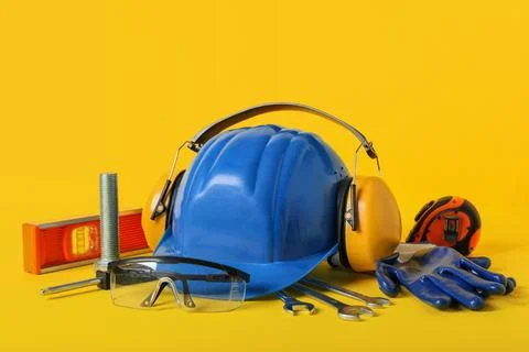 Hardhat with construction tools on yellow background Stock Photos