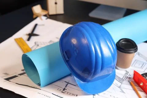 Hardhat with house plan and coffee cup on engineer's desk in office Stock Photos