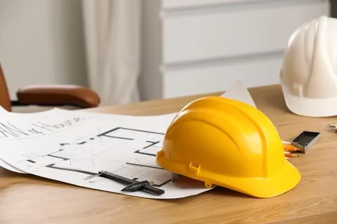 Hardhat with house plan on desk in office Stock Photos