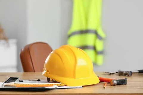 Hardhat with work tools on desk in office Stock Photos