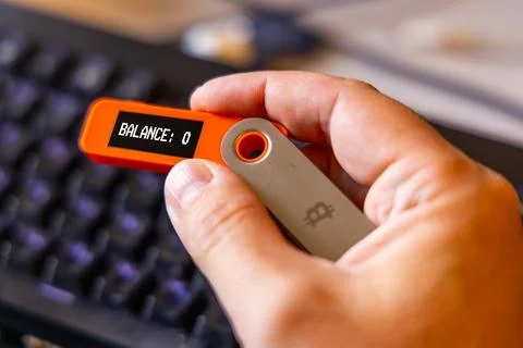 Hardware Bitcoin wallet in a hand with message Balance 0 on screen Stock Photos