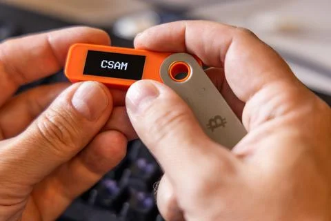 Hardware Bitcoin wallet in a hands with CSAM message on screen Photos