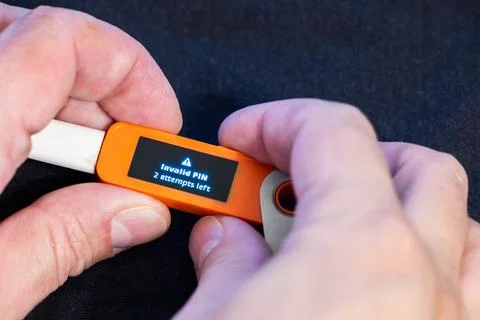 Hardware Bitcoin wallet with message Invalid PIN in hands of Caucasian male Stock Photos