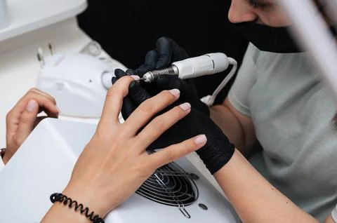 Hardware manicure. Close-up of a manicure master filing gel polish with a nail Stock Photos