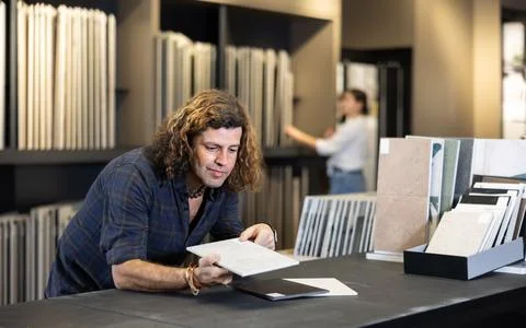 In hardware store,man chooses ceramic tile with modern pattern for bathroom Foto stock