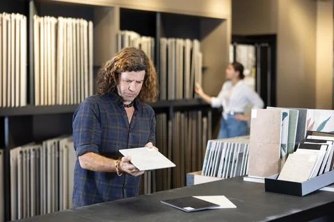 In hardware store,man chooses ceramic tile with modern pattern for bathroom 写真素材