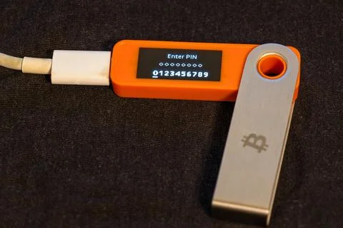Hardware wallet displaying PIN entry on dark surface Stock Photos