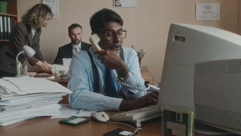 Hardworking Employee Working on Computer and Answering Phone Call in 80s Stock Footage 280261535
