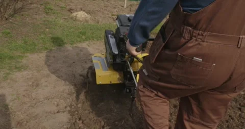 Hardworking farmer in overalls preparing the land for planting by plowing the 스톡 동영상 333231203