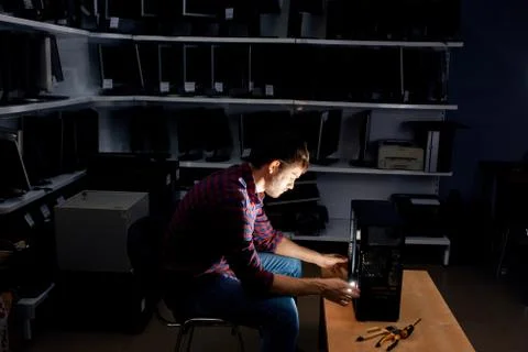 Hardworking IT specialist working with a computer in the dark room at night Stockfoto's