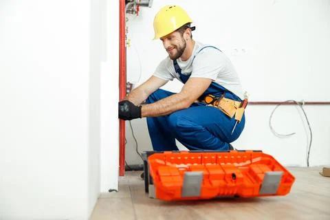 Hardworking technician, plumber in uniform using tools from toolbox while Foto stock