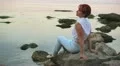 The harmonous woman sits on the seashore in the evening HD Footage