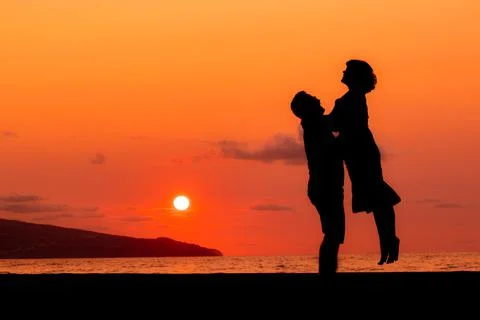 Harmony between couple at the beach, silhouette during sunset, lovers. Stock Photos