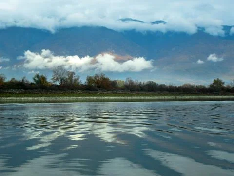 Harmony of nature -  clouds, trees and mountain hills over the lake waters Stock Photos