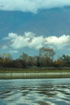 Harmony of nature - a sky with clouds, trees in autumn over the lake waters Stock Photos