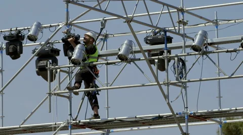 Harnessed electrician technician setting up/rigging lights for the concert Stock Footage 54467437