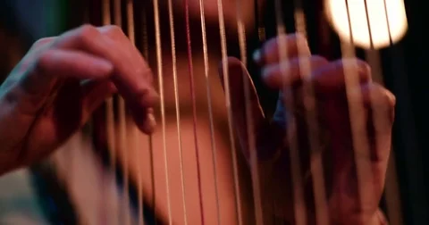Harp playing and beautiful arms touching strings in close up 4K Stock Footage