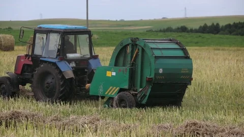 Harvest, the tractor cleans the hay and dashes haystacks in the field. Stock Footage