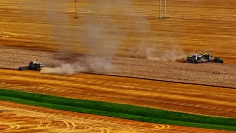 Harvesters Creating Dust Clouds in a Sunlit Wheat Field Stock Footage 333315910