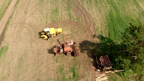 Harvesters stand on wide field between tree and road aerial Stock Footage 139443164