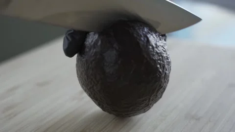 Hass avocado being cut into halves by female hands in black gloves. Close up Stock Footage 243283503