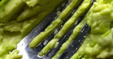 Hass avocado pulp being stirred with a fork, slow motion close-up Stock Footage 301017369