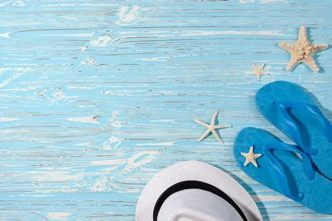 Hat and beach flip flops on a blue wooden background. Starfish. View from above Stock Photos