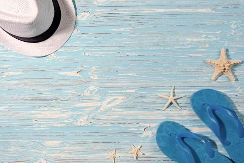 Hat and beach flip flops on a blue wooden background. Starfish. View from above Stock Photos