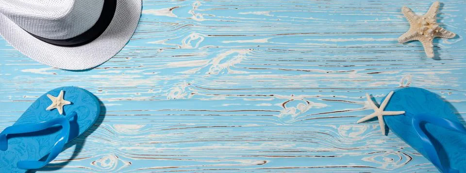 Hat and beach flip flops on a blue wooden background. Starfish. View from above Stock Photos