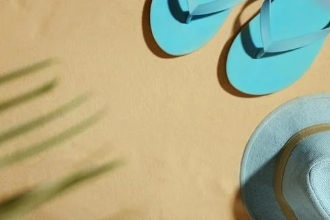 Hat and flip flops on beach sand, top view. Space for text Stock-Fotos