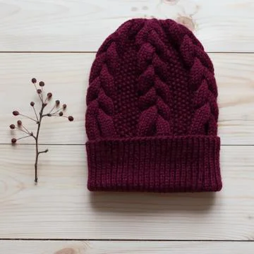 Hat bound manually of dark red wool near the twig on which the red berries. Stock Photos