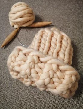 Hat made of sheep wool of large knitting. With a ball of yarn and wooden spokes. Stock Photos