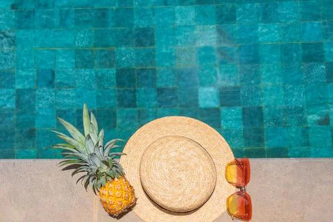 Hat, pineapple, glasses by the pool. Summer vacation concept. Stock Photos