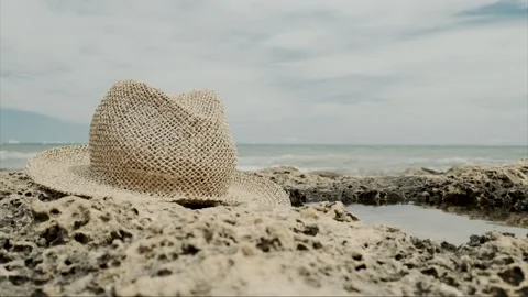 Hat on rocks on the shore of the beach Stock Footage 138786315