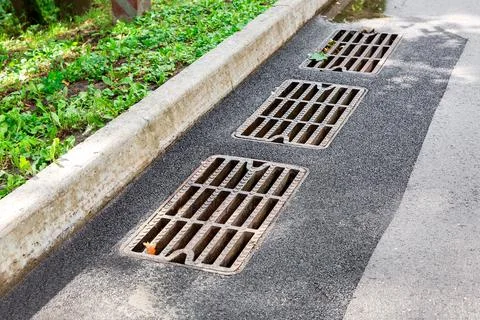 Hatch storm system with a rusty grate in the asphalt road surface. 写真素材