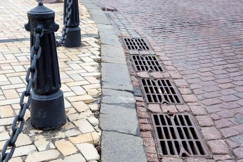 Hatches of the drainage system of the road paved with paving stones. Stock Photos