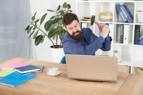 Hate my job. dealing with error. overworked man crush laptop with hammer Foto stock
