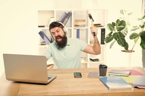 Hate office routine. Man bearded guy headphones office swing hammer on computer Stock Photos