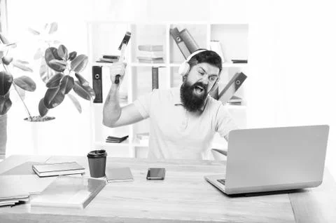 Hate office routine. Man bearded guy headphones office swing hammer on computer Foto stock