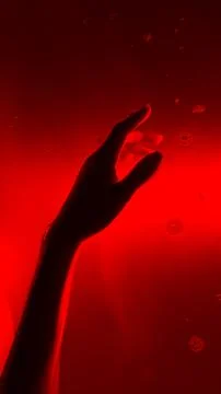 A Haunting Glimpse Beneath the Surface: A Hand Reaches Out Against a Vivid Red Stock Photos