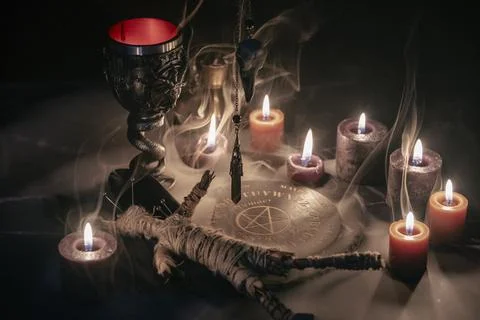A haunting occult setup featuring a pendulum, mystical symbols, candles, a Stock Photos